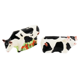 Seen are a pair of vintage Mann cow salt and pepper shakers. One cow is standing and the other cow is laying down. Both have horns.