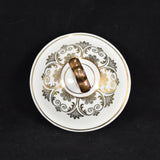 The top of the vintage Seltmann covered sugar bowl is shown in this photograph. It is white with gold accents and trim. Some minor wear is shown on the top of the handle of the lid. It was photographed on a black background.