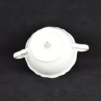 The bottom of the vintage Seltmann sugar bowl is shown. It is white in color with a green back stamp in the middle. Photographed on a black background.