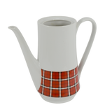 Shown is a c. 1950 - 1960's Winterling Roslau Coffee Pot. It is white and has a red, black and white check pattern around the bottom. It has a long elegant white handle and spout. There is no lid with the coffee pot