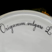 Origanum vulgare L. is written in cursive and is black in color. The underside is white porcelain and is shiny.