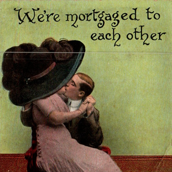 This is a partial view of the c. 1910's postcard. On the top it says: We're mortgaged to each other. There is a woman with a large hat on sitting on the lap of a man. They are holding hands and kissing.