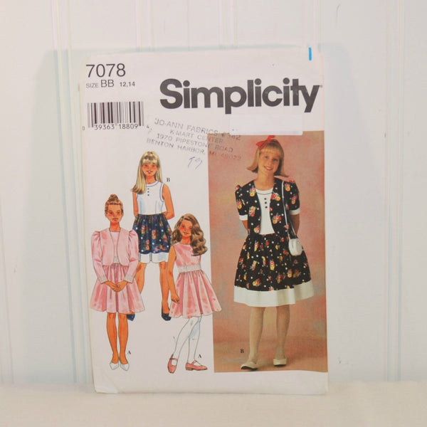 The front of the paper envelope for Simplicity 7078 is shown here propped up on a white background. On the left are three illustrated little girls, each wearing clothing that can be made from this sewing pattern. On the right is a young girl also wearing clothing that can be made from this sewing pattern. There is a faint store stamp on the front also.