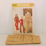 The factory folded tissue paper sewing pattern is laying in front of the propped up paper envelope for vintage Simplicity 5851.