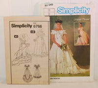Shown is the paper instruction sheet for Simplicity 6766. On the front it shows two versions of the dress that can be made from this pattern. It is upright and to the left of the paper envelope.