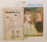 Shown is the paper instruction sheet for Simplicity 6766. On the front it shows two versions of the dress that can be made from this pattern. It is upright and to the left of the paper envelope.