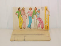 The factory folded tissue paper sewing pattern is laying in front of the paper envelope for Simplicity 5587.