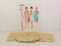 The tissue paper pattern is laying in front of the paper envelope for Simplicity 5910. The tissue paper pattern is partially cut and all pieces are accounted for.
