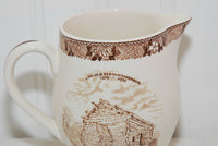 A close up of the brown transferware floral design that goes all the way around the top of the creamer.