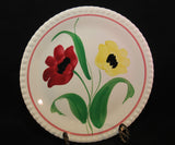 A close up of the upright plate featuring one red poppy and one yellow poppy. Both have dark interiors. There is a thin red line just within the outside of the plate.