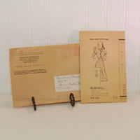 Seen in this photo is the envelope and instruction sheet for a vintage mail order Marian Martin Design 9377. It is c. 1940's. The envelope is propped up on a metal stand.
