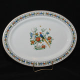 Featured is a vintage Onondaga Pottery platter, circa 1919-?. It is oval in shape with a floral border and in the center, features flowers and a multi colored bird, which appears to be some sort of pheasant. The background of the platter is white.