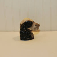 This is a side view of the cocker spaniel head bookend. The ears are black and the rest of the dog is mostly white. It is on a white background.