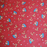 Shown is vintage fabric from the late 1990's. It features Santa in a sleigh and he is holding a Christmas tree. The sleigh is also being pulled by two reindeer. There are white snowflakes and presents interspersed. The background of the fabric is red in color. 