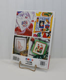 The photo shows the back cover of the cross stitch paperback book. It shows four different complete cross stitch projects.