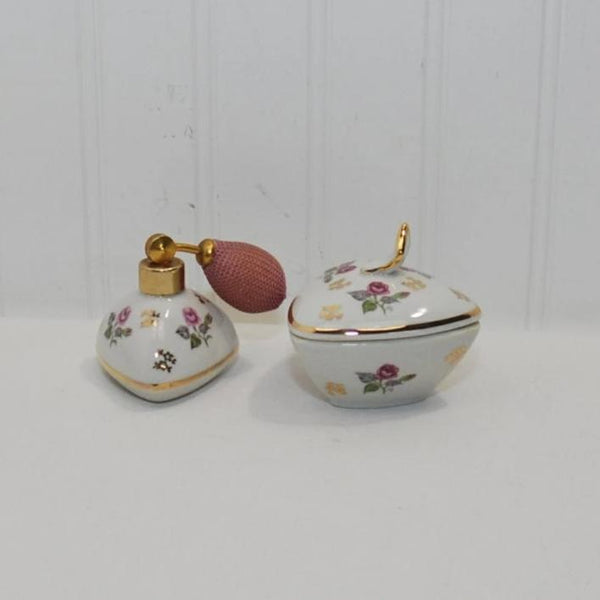 A vintage Bavaria dresser set from circa pre-1989. It was made in West Germany. The set consists of a perfume, complete with atomizer and a covered dish. Both pieces are trimmed in gold and feature delicate roses.