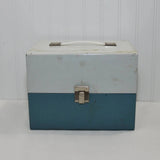 The front of the vintage Smith-Victor metal home movie carrying case. This case is from circa 1960-1970's. It's two tone in color, it has a silver color metal latch in the front and the top flips opens. There is a metal and plastic handle on top.