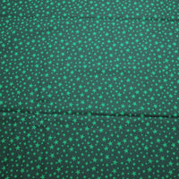 A photo of Christmas everyday by Ann Wanke. The fabric has a dark green background with lighter colored green stars. The stars are a variety of sizes. The fabric was made by Henry Glass and company.