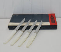 A photo of the four knives leaning on top of the box. The edges of the knives are serrated.