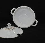 And interior view of the soup tureen, which is completely white. It is laying on it's side on a black background. The lid is place in front and to the left of the soup tureen.
