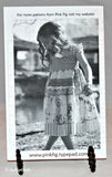 Shown is the a black and white photo that is on the instruction sheet. The young girl is wearing a dress that can be made with this pattern.