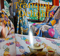 A page from the book that says Tranquil Delights and shows a quilt draped over a wood rocking chair. There is a table in front of the quilt/rocking chair that has a quilted tablecloth on it and also a teapot, tea cup with tea inside and a creamer.