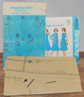 The paper instruction sheet is shown propped up in front of the paper envelope for Simplicity 6850. The tissue paper pattern is laying in front of the instruction sheet and envelope. The pattern is factory folded and unused.