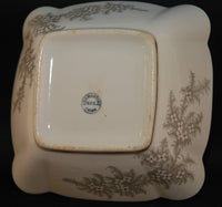 Another view of the bottom of the antique Adamantine serving bowl and the backstamp with states Adamantine, WPC, China. There is a delicate floral design on two fo the corners.