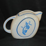 Shown is a vintage pitcher that was handpainted and made in Japan. It is a creamy white color with beautiful blue decoration around the edge of the opening, in the middle of the side and on the handle.