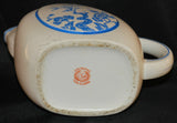 Shown is the backstamp on the made in Japan pitcher. The backstamp is red in color and has a laurel leaf around what appears to be the head of an elephant. The words Hand Painted are above and the words Made in Japan, below. There is signs of wear on the bottom and also some faint scuffing on the bottom of the pitcher.