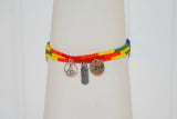 A view of three different Pride bracelets are shown. One has a peace symbol charm, another one has a Believe charm and the third one has a round Love charm. All seed beads are in the same order of color.